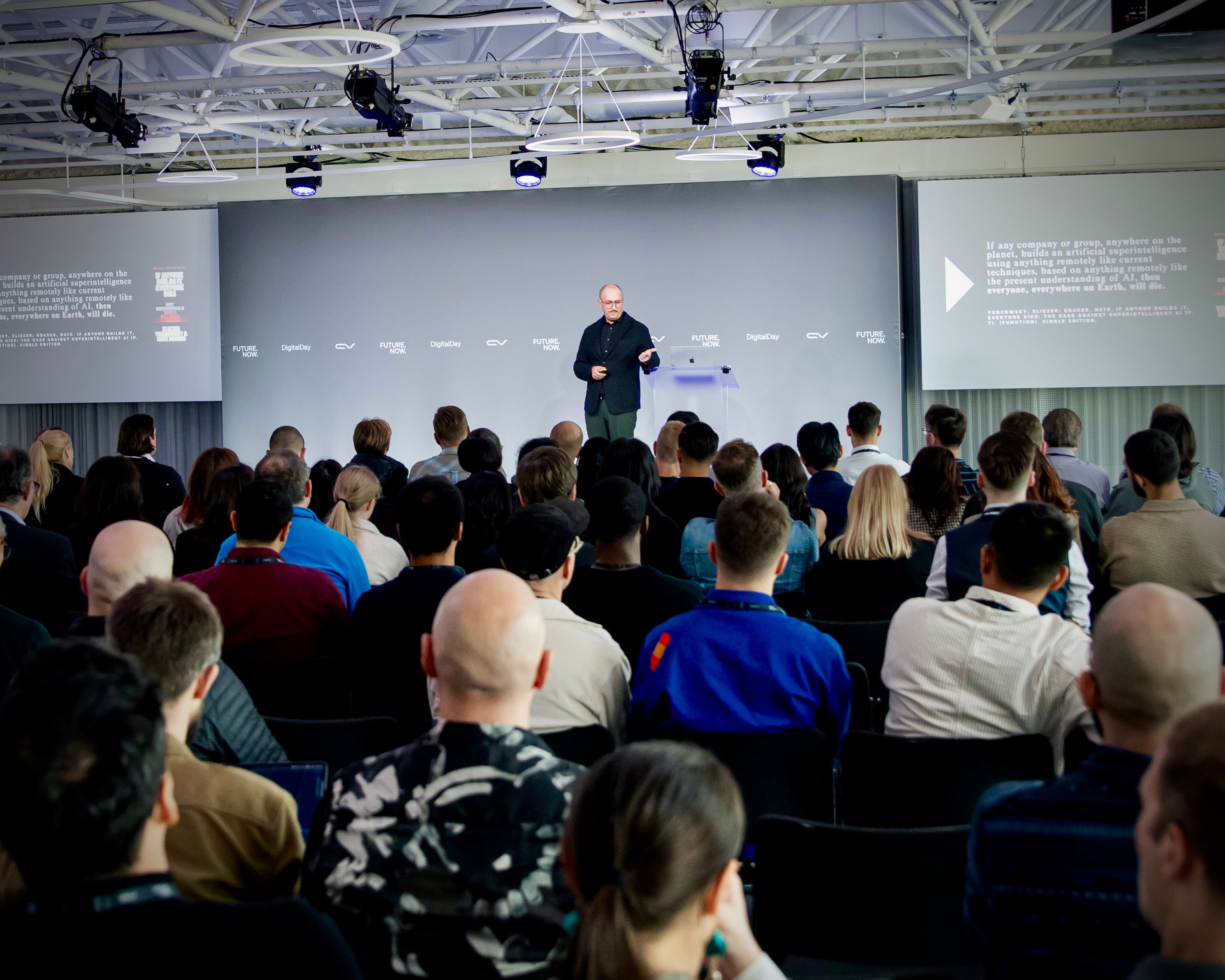 James Poulter delivering an AI keynote presentation to a large audience